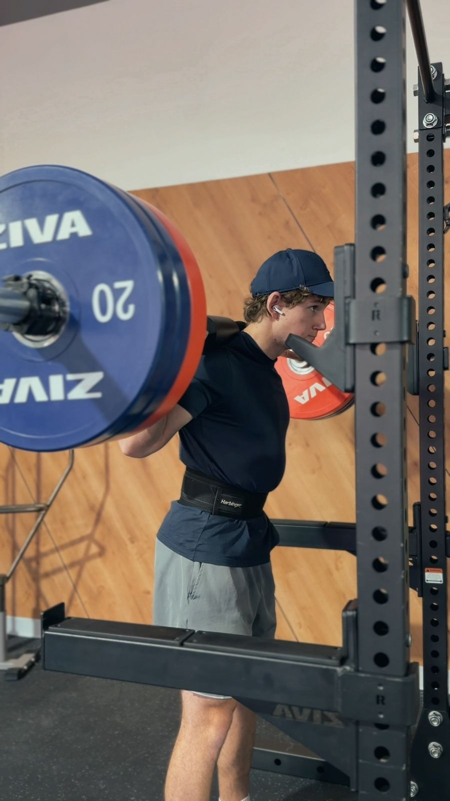 Gabriel setting up under a loaded barbell in a squat rack